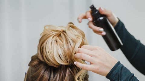 Eine Frau bindet einer anderen Frau einen Dutt. - Foto: frantic00/iStock