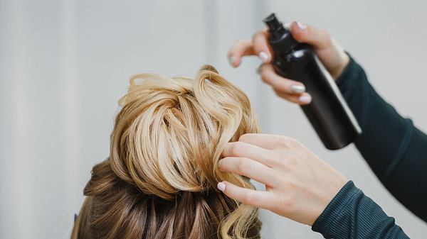 Eine Frau bindet einer anderen Frau einen Dutt. - Foto: frantic00/iStock