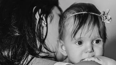 Schwarz-Weiss-Aufnahme mit Mutter, die ihr Baby auf dem Arm hält. - Foto: iStock/Photographer and Illustrator