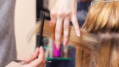 Nahaufnahme - Friseurin macht einen Haarschnitt mit einer Schere. - Foto: dimid_86/iStock