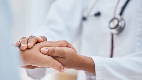 Ärztin hält die Hand eines Patienten - Foto: PeopleImages/iStock