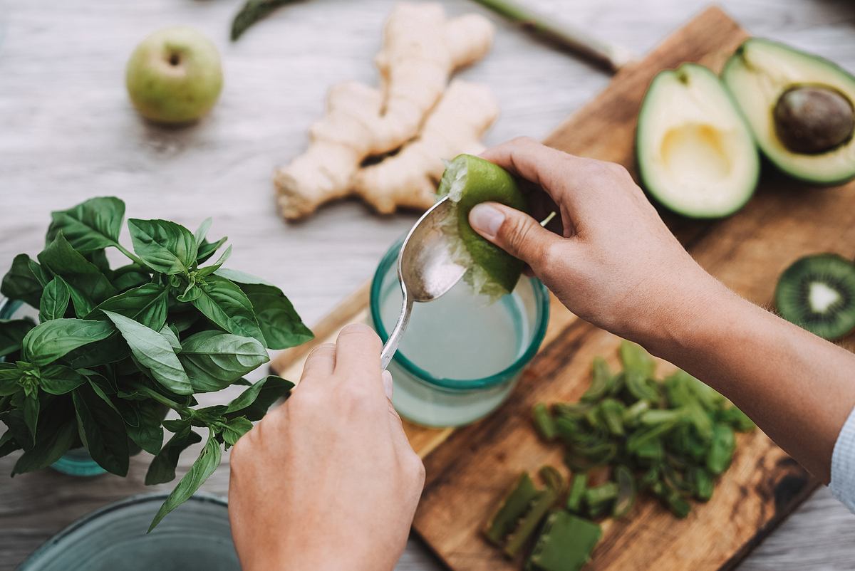 Frau bereitet Detox-Saft mit grünem Gemüse zu