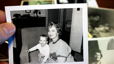 Schwarz-Weiß Foto von einem Baby und seiner Mutter, die in die Kamera lächeln. - Foto: iStock/catscandotcom