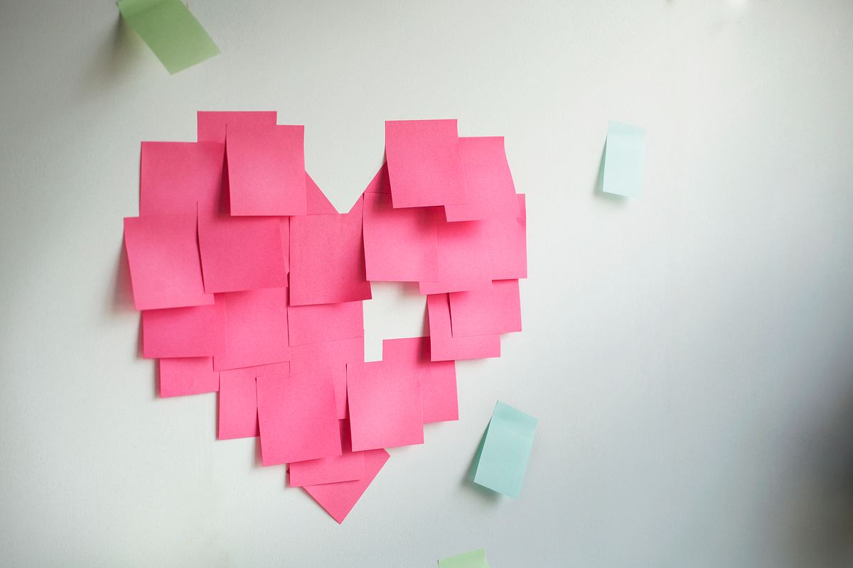 Pinke Post-its kleben an einer Wand in Herzform