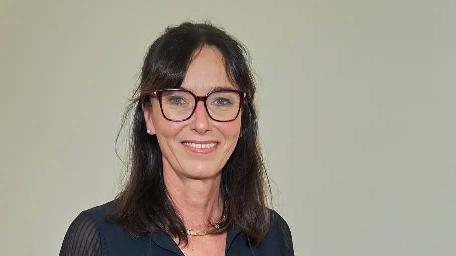 Dr. Heide Rezepa-Zabel steht vor einer weißen Wand. Sie lächelt in die Kamera und trägt eine dunkle Bluse.