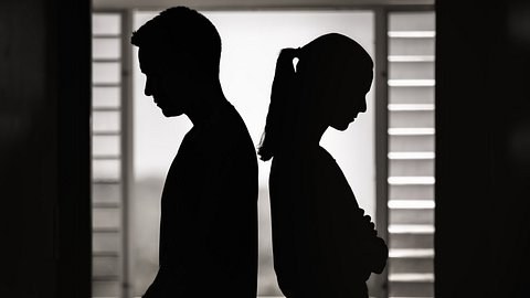 Schwarz-weiß Silhouetten von einem Paar, das Rücken an Rücken zu einander steht. - Foto: kieferpix/iStock