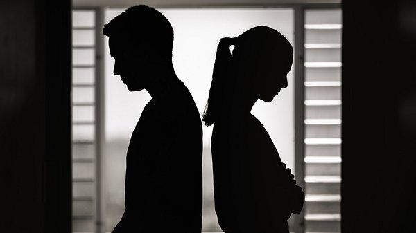 Schwarz-weiß Silhouetten von einem Paar, das Rücken an Rücken zu einander steht. - Foto: kieferpix/iStock