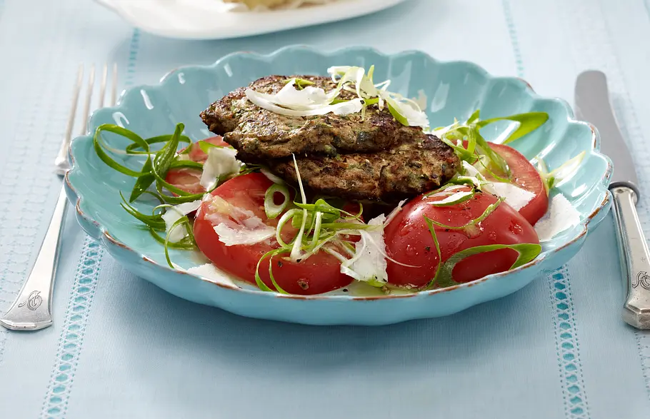 Eiweiß Gericht: Frikadellen mit Tomatensalat Zucchini-Hack-Frikadellen auf docken Tomatenscheiben mit Parmesan und Lauchzwiebeln.