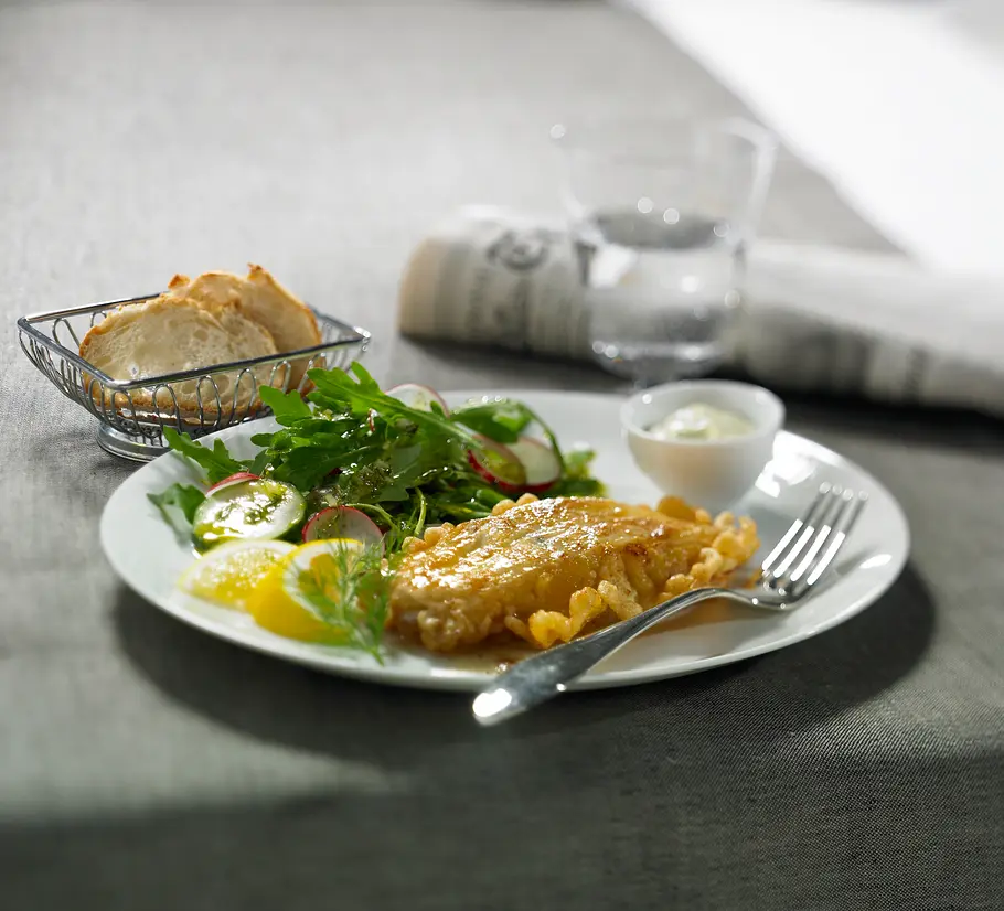 Eiweiß Rezept für Kabeljau in Eihülle Kabeljau in Eihülle mit Salat. Dazu Brotscheiben im Hintergrund.