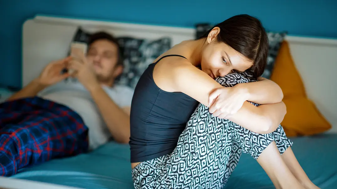 Traurige Freundin, die neben ihrem Freund auf der Bettkante sitzt - Foto: zoranm/iStock Traurige Freundin, die neben ihrem Freund auf der Bettkante sitzt - Foto: zoranm/iStock