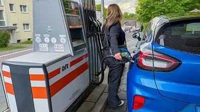 Eine Frau tankt ihr blaues Auto. - Foto: IMAGO / HMB-Media