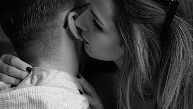 Frau küsst Mann am Ohr - Foto: Symbolbild RobertoDavid/iStock