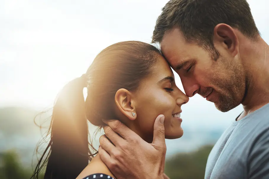 Erotische Liebesgeschichte Nahaufnahme eines verliebten heterosexuellen Paares, das sich Stirn an Stirn beinahe küsst und anlächelt.