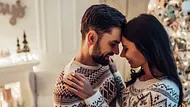 Ein verliebtes Paar tanzt und lächelt sich in einer weihnachtlich geschmückten Wohnung an - Foto: Vasyl Dolmatov/iStock