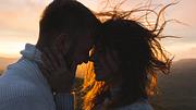 Paar teilt einen intimen Moment vor der untergehenden Sonne in den Bergen. - Foto: olegbreslavtsev / iStock