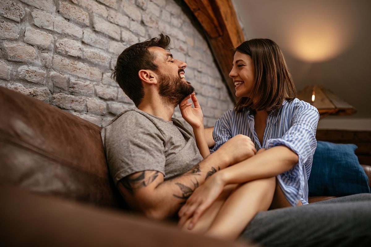 Paar teilt einen zärtlich-lustigen Moment auf dem Sofa.