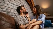 Paar teilt einen zärtlich-lustigen Moment auf dem Sofa. - Foto: bernardbodo / iStock