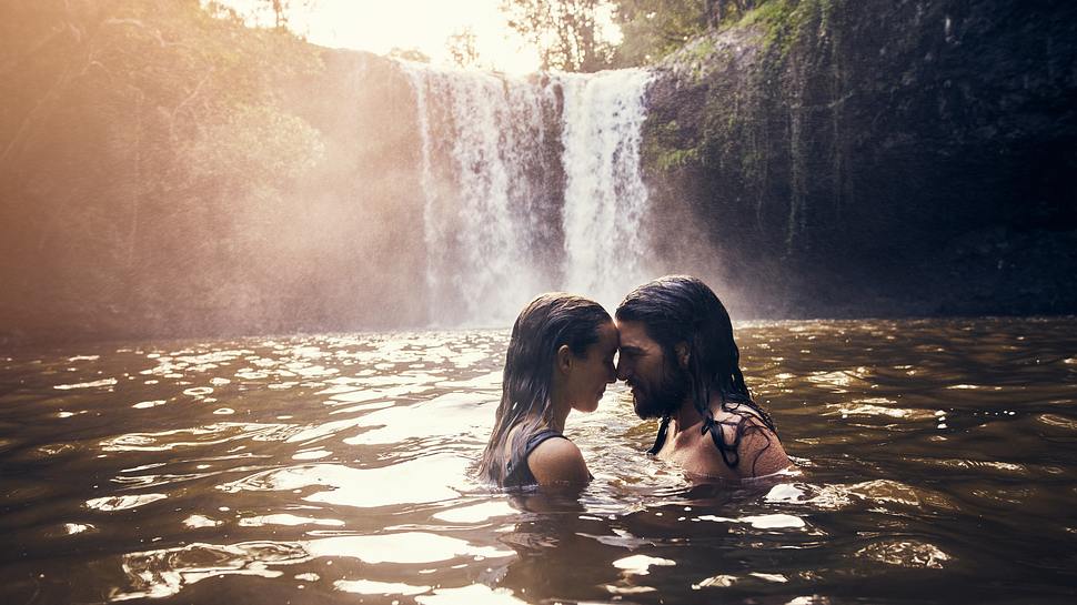 Paar teilt einen intimen Moment vor einem kleinen Wasserfall. - Foto: pixdeluxe  / iStock