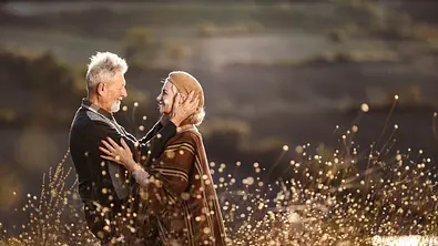 Liebespaar steht ihm Frühling auf einem Feld und teilt einen innigen Moment. - Foto: skynesher / iStock