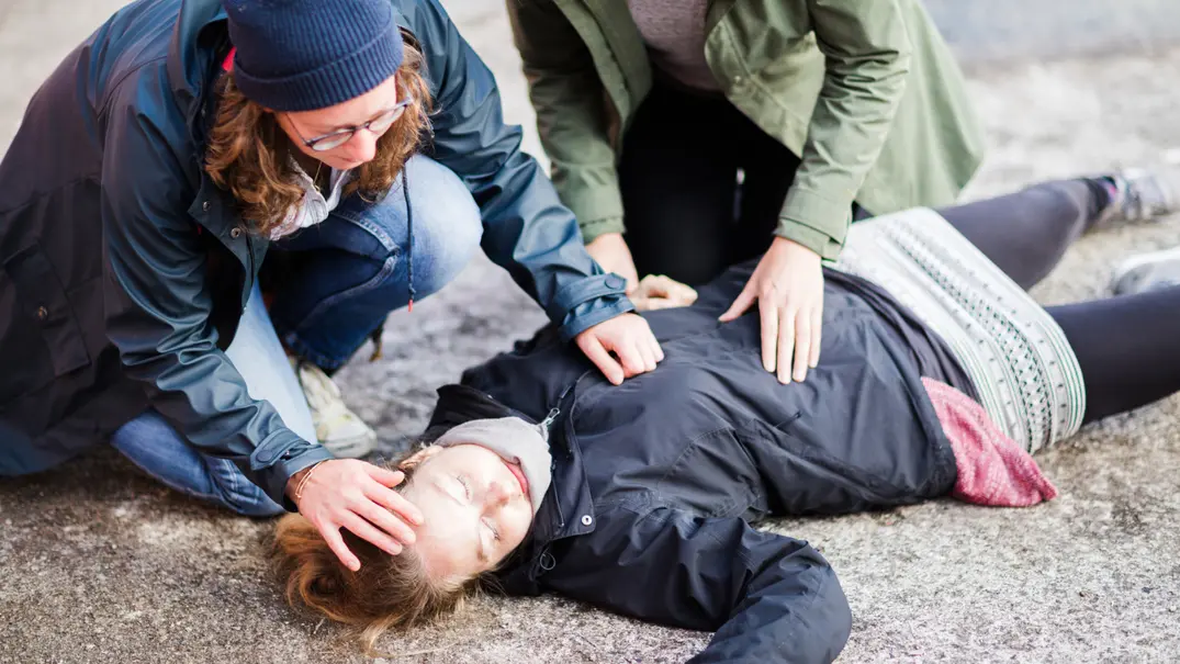 Zwei Frauen beugen sich über eine bewusstlose Frau am Boden - Foto: iStock/Jan-Otto Zwei Frauen beugen sich über eine bewusstlose Frau am Boden - Foto: iStock/Jan-Otto