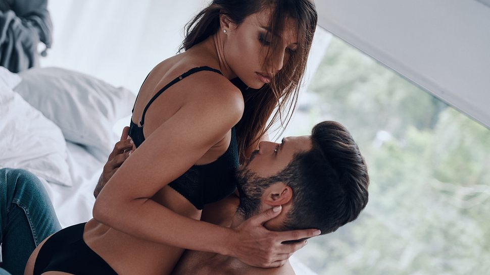 Frau und Mann sind im Bett und leicht bekleidet intim miteinander. - Foto: g-stockstudio/iStock