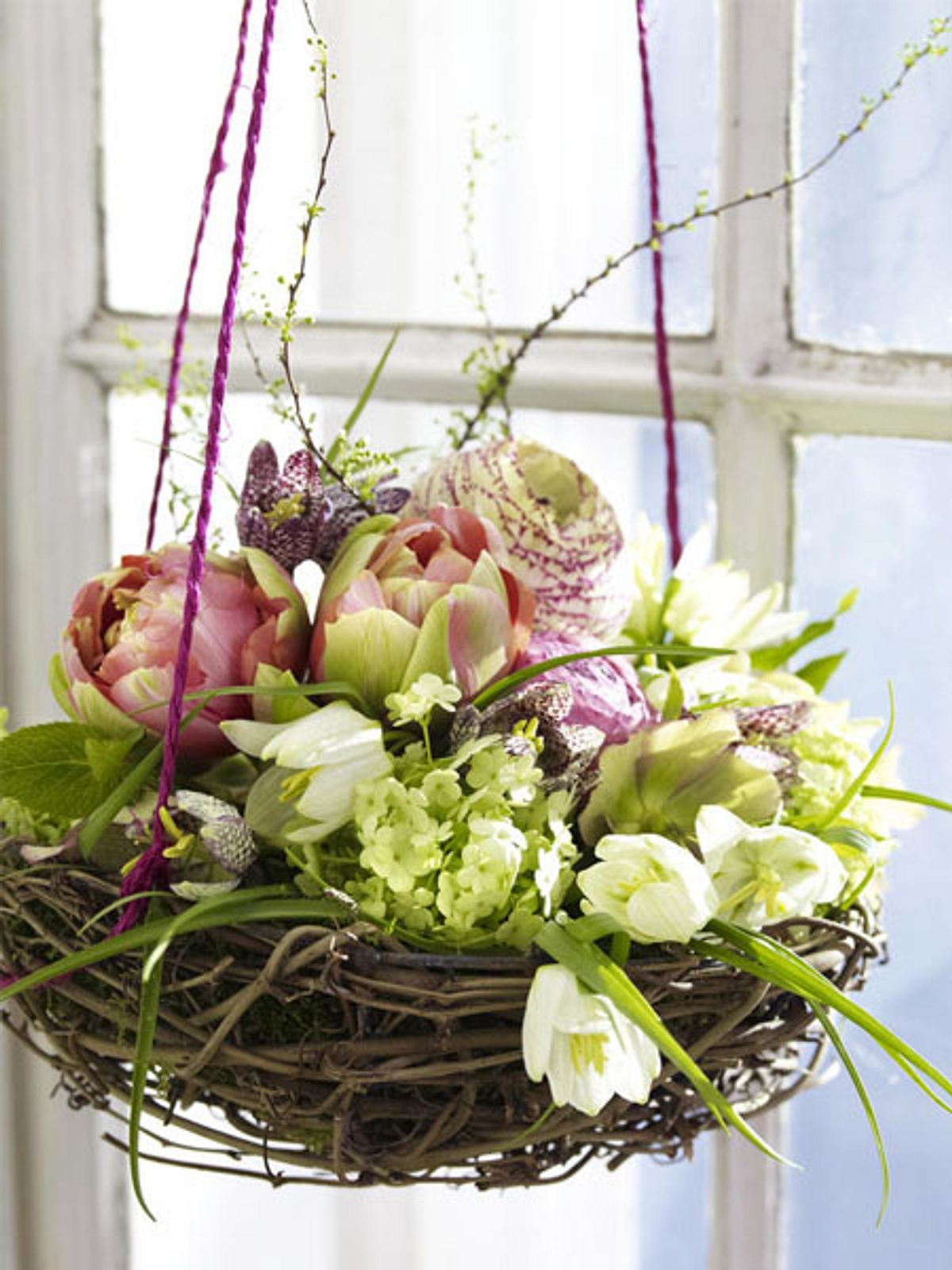 Ein Osternest mit Frühlingsblumen als Fensterdeko: Die Idee ist nicht nur ausgefallen, sie vereint auch Oster- und Frühlingsdeko in einem.