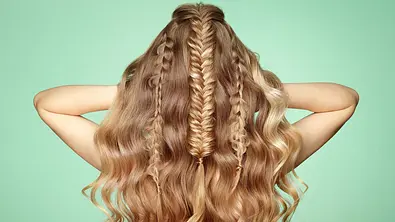 Frau mit Wellen steht mit dem Rücken zur Kamera und präsentiert ihre Half-up-Frisur mit Flechtelementen.  - Foto: heckmannoleg/iStock 