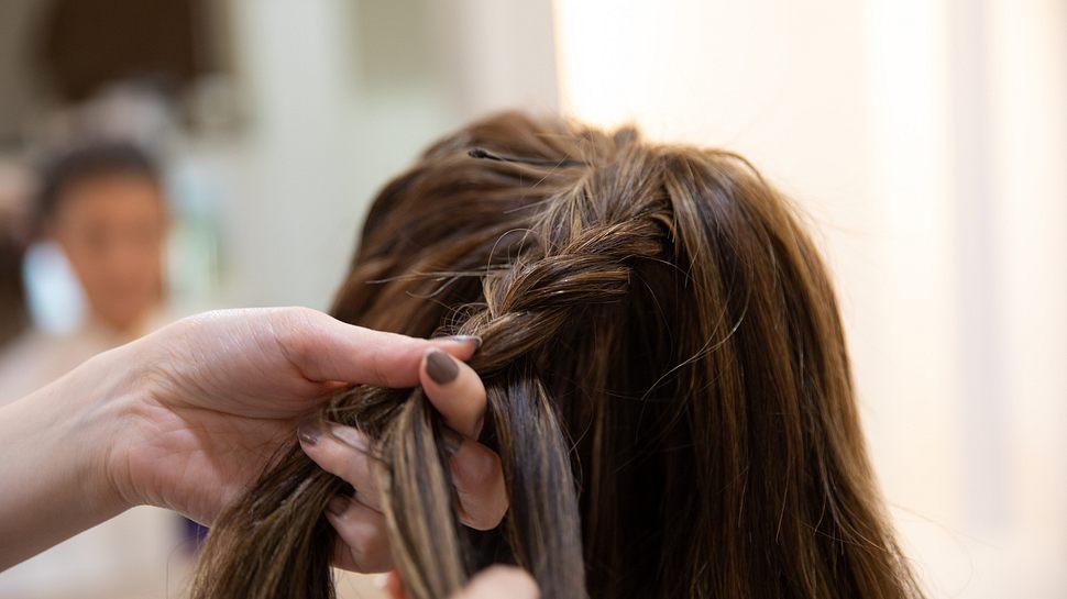 Frau mit braunem Haar bekommt einen Zopf geflochten. - Foto: kumikomini/iStock (Themenbild)