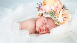 Baby liegt mit Blumenkrone in einem Meer aus Tüll (Themenbild) - Foto: druvo/iStock