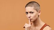 Frau mit kurzen Haaren hält Finger an die Lippen zum Schweigen (Themenbild) - Foto: AndreaObzerova/iStock