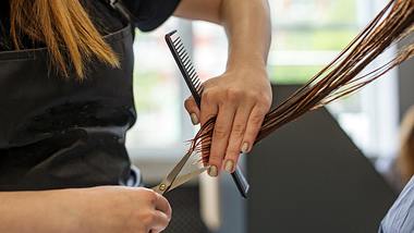 Friseurin schneidet die Haare einer Frau mit mittellangen Haaren - Foto: Olha Romaniuk/iStock