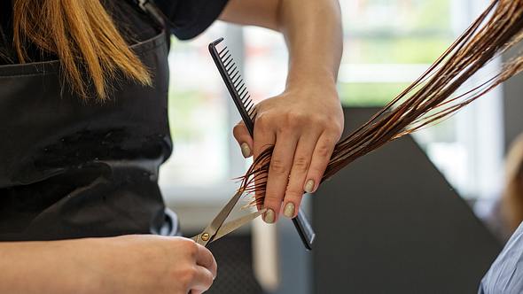 Friseurin schneidet die Haare einer Frau mit mittellangen Haaren - Foto: Olha Romaniuk/iStock