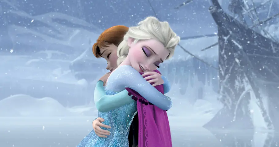 Frozen - Die Eiskönigin Elsa und Anna umarmen sich. Um sie herum schneit es, alles ist eingefroren.
