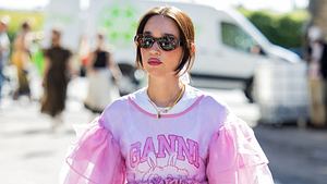 Frau in Tshirt mit Ganni Print und pinker Rüschen Bluse - Foto: Getty Images / Christian Vierig