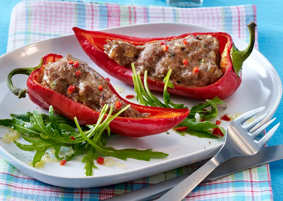Gefüllte Spitzpaprika mit Rauke: Das leckere Eiweß-Rezept Zwei Hälften gefüllte Spitzpaprika mit Hackfleischfüllung dazu Rauke als Garnitur.