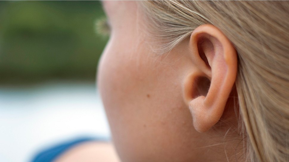 Seitlicher Blick von hinten auf das Ohr einer blonden jungen Frau oder eines Mädchens (Themenbild) - Foto: Bonerok/iStock