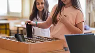 Mädchen legt ihr Smartphone in eine Box. Schule, die sicherstellt, dass Schulkinder während des Unterrichts keine Telefone benutzen. - Foto: Dobrila Vignjevic/iStock