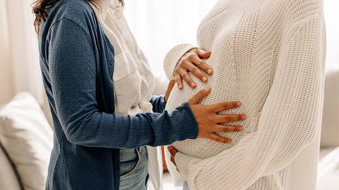 Nicht wiederzuerkennende junge Frau, die den schwangeren Bauch ihrer Leihmutter berührt - Foto: JLco - Julia Amaral/iStock