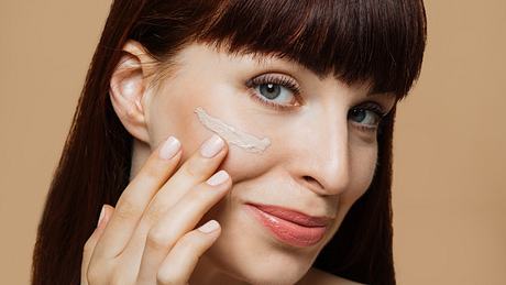 frau trägt sich getönte creme im gesicht auf - Foto: iStock / undefined