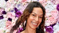 Gisele Oppermann steht mit strahlendem Lächeln und offenen Haaren vor einer Blumenwand. - Foto: IMAGO / Future Image