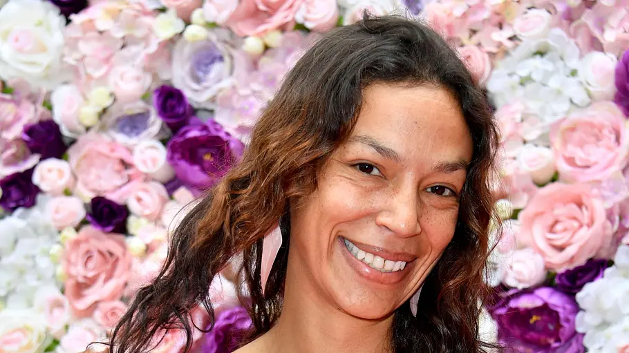 Gisele Oppermann steht mit strahlendem Lächeln und offenen Haaren vor einer Blumenwand. Gisele Oppermann steht mit strahlendem Lächeln und offenen Haaren vor einer Blumenwand.
