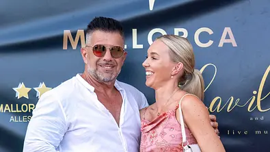 Marco Gülpen trägt eine Sonnenbrille. Tamara Gülpen schaut ihn lachend an. - Foto: IMAGO / nicepix.world
