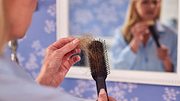 Frau entfernt Haare aus Haarbürste (Themenbild). - Foto: AdobeStock / Monkey Business