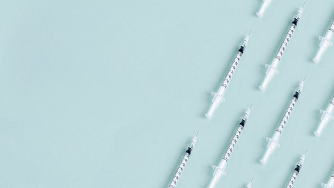 Syringe pattern on blue background with copy space. - Foto: Selcuk1/iStock