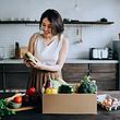 Frau packt eine Box mit Nahrungsmitteln in der Küche aus. - Foto: iStock/AsiaVision 