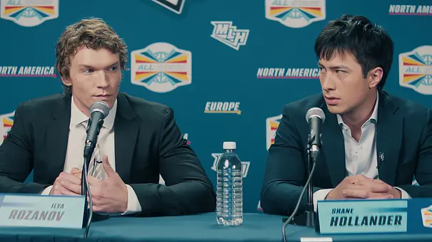 Die beiden Hauptdarsteller der Serie „Heated Rivalry“ sitzen an einem Rednerpult. - Foto: HBO Max