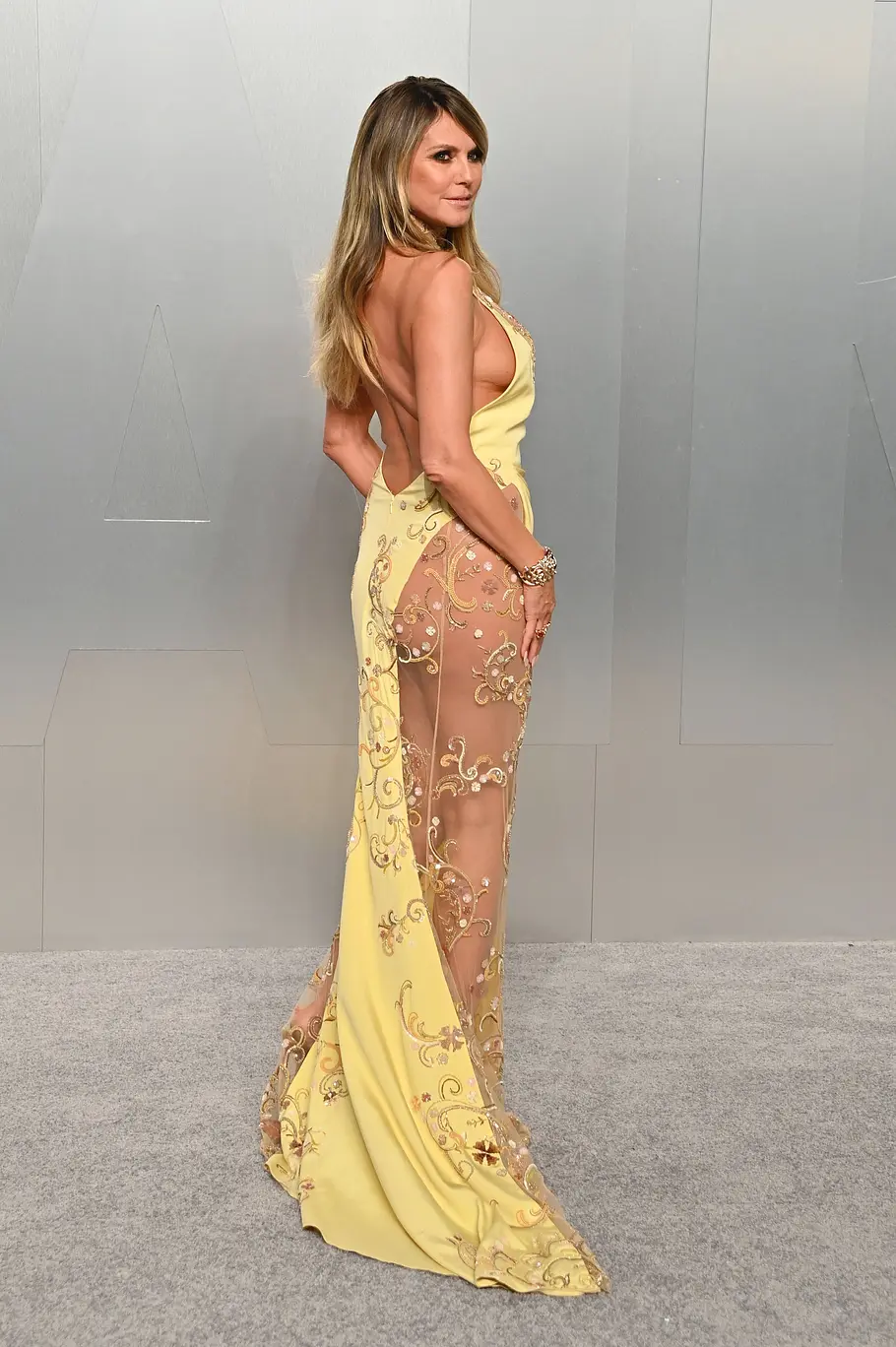 Heidi Klum im gelben Kleid mit Rückenausschnitt und transparenten Details