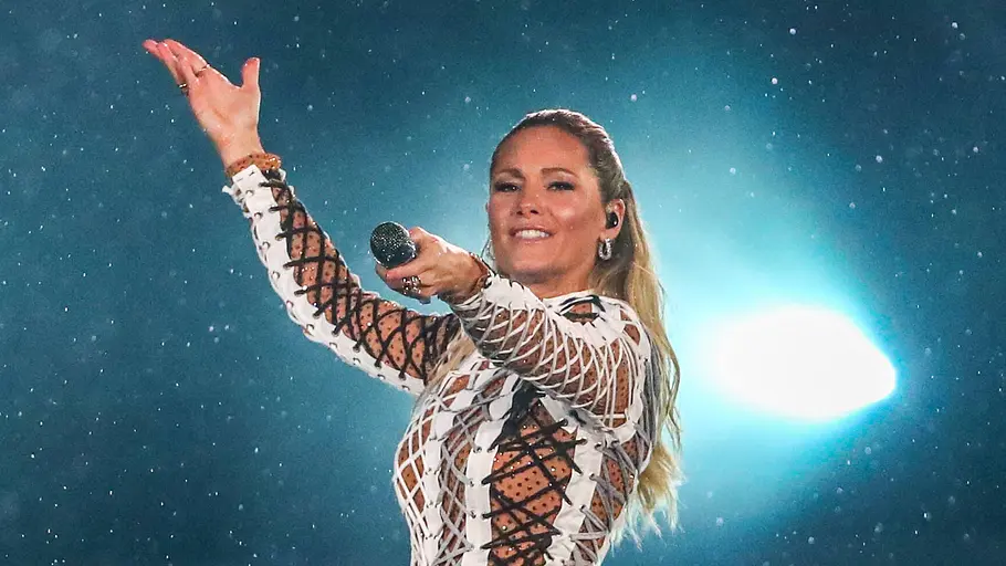 Helene Fischer in der Tagesschau: Kritik Konzertpreise Helene Fischer am 20.08.2022 bei einem Konzert. In einem Fransenkleid steht sie vor zwei hellen Scheinwerfern.