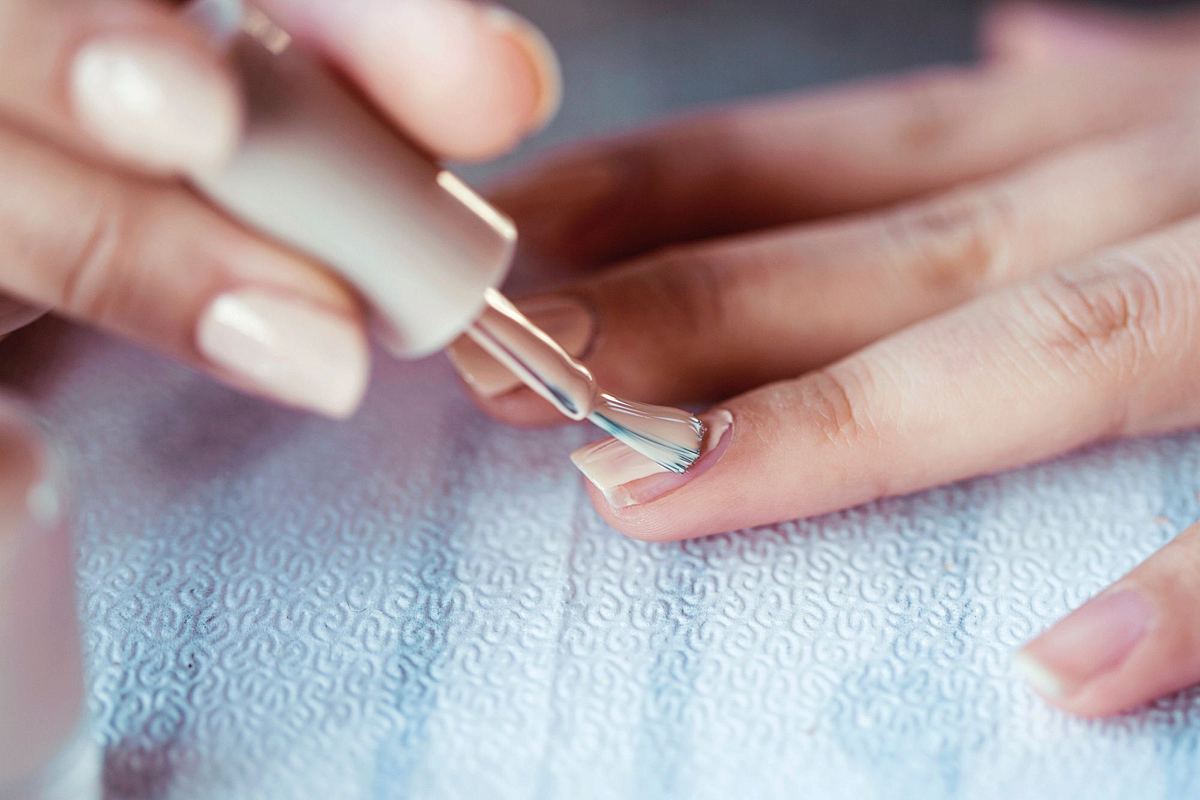 Nahaufnahme von Frauenhänden, die gerade Nagellack aufträgt.