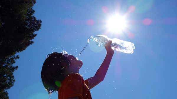 Frau schüttet sich Wasser ins Gesicht und die Sonne scheint (Themenbild) - Foto: AlesVeluscek/iStock (Themenbild)